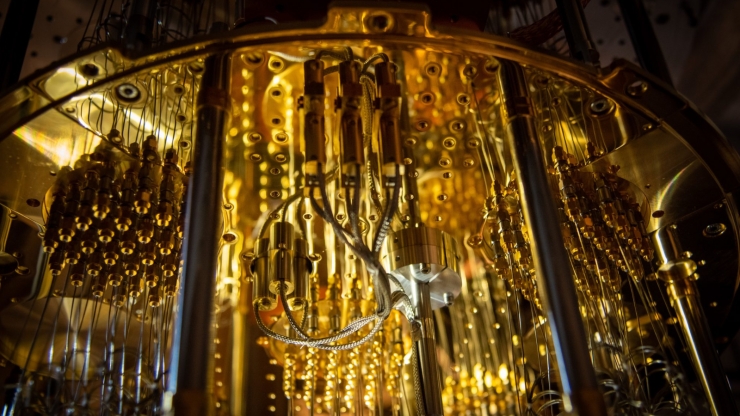 complex machinery with vials and tubes hanging down from a circular ceiling all bathed in yellow-gold light
