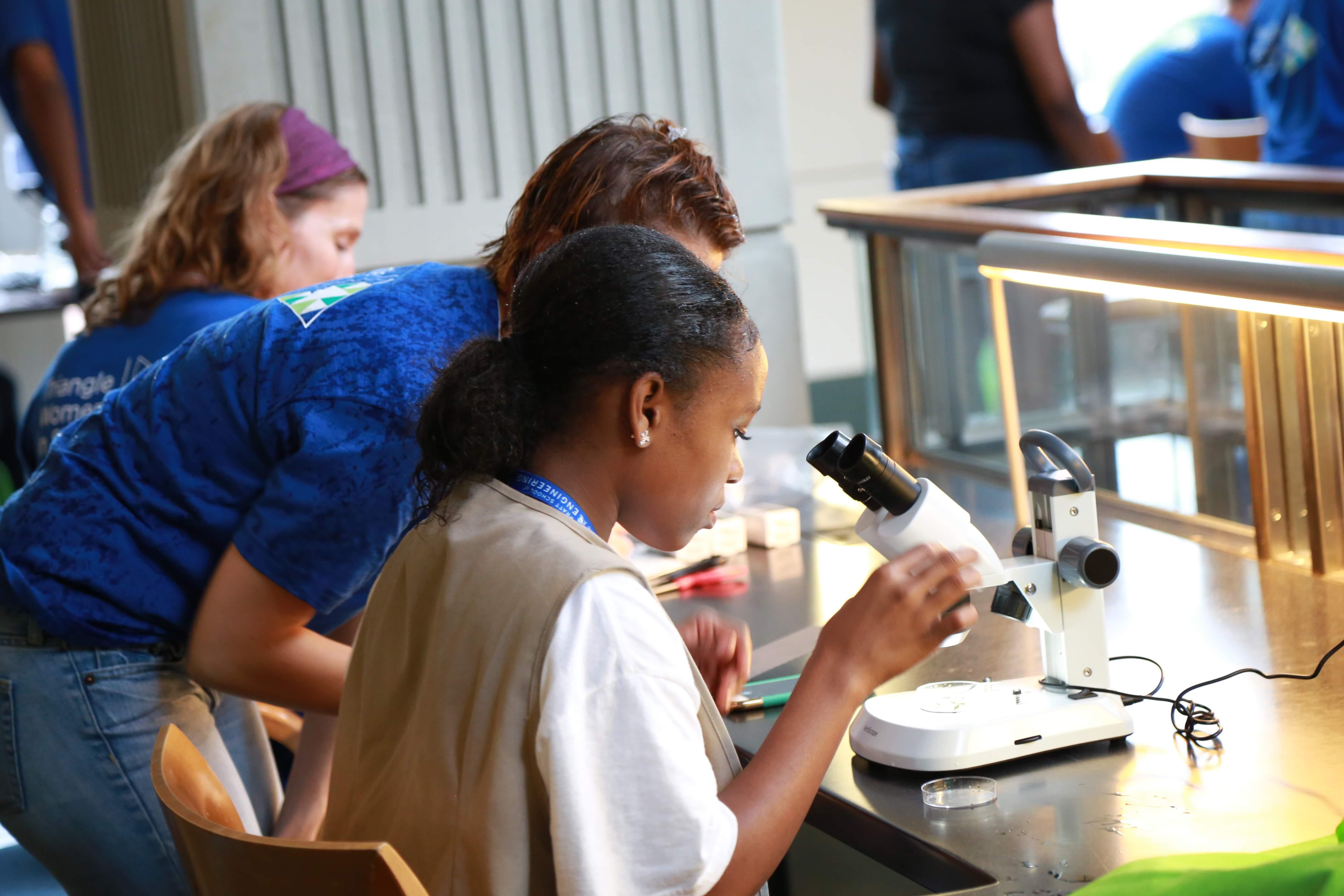 Program participant and staff member using a microoscope